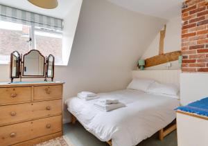 a bedroom with a bed and a dresser and a mirror at Anchor Cottage in Woodbridge