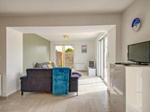 ein Wohnzimmer mit einem Sofa und einem TV in der Unterkunft Holiday Home Les Volets Bleus - LTB307 by Interhome in La Turballe