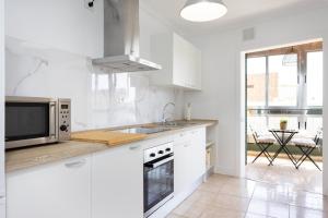 eine weiße Küche mit Mikrowelle und Spüle in der Unterkunft EDEN RENTALS Kings Kapital in Santa Cruz de Tenerife
