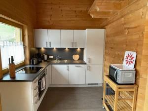 W kuchni znajduje się biała lodówka i kuchenka mikrofalowa. w obiekcie Apartment Jochblick by Interhome w mieście Niederau