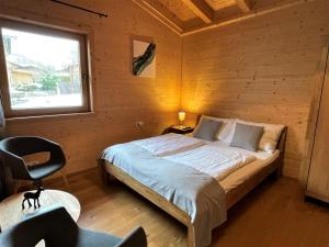 sypialnia z łóżkiem, krzesłem i oknem w obiekcie Apartment Jochblick by Interhome w mieście Niederau
