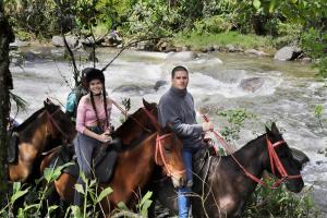 a man and a woman riding horses by a river at El Rancho de Salento in Salento