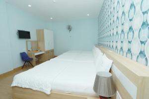 a bedroom with a large white bed with a blue wall at Lys Hotel in Buon Ma Thuot