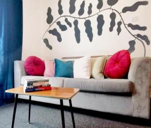 ein Wohnzimmer mit einem Sofa mit Kissen und einem Tisch in der Unterkunft 5-Bedroom Townhouse - Ideal for Groups, Families or Contractors by Glos Homes Ltd in Cheltenham