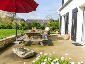 eine Terrasse mit einem Picknicktisch und einem roten Regenschirm in der Unterkunft Holiday Home Ty va Zud by Interhome in Lampaul-Ploudalmézeau