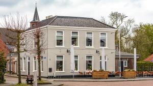 a large white house with a steeple on a street at Hotel Restaurant Toxopeus in Anjum