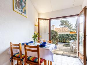 een eetkamer met een tafel en stoelen en een raam bij Holiday Home Hameau de Talaris-4 by Interhome in La Palmyre