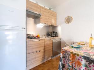 una cucina con armadi in legno e un tavolo con una tovaglia di Holiday Home Les Maisons de la Plage-7 by Interhome a Le Grau-du-Roi Altre 18 foto