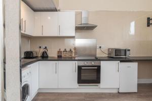 cocina con armarios blancos y microondas en Contemporary 3 Bed City Centre Appartment - Ensuite en Edimburgo