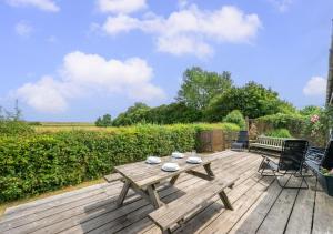 a wooden deck with a table and chairs on it at Barn Owl Oxley Dairy in Hollesley