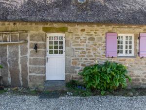 een stenen gebouw met een witte deur en twee ramen bij Holiday Home Chaumiere Natelliou by Interhome in Trégunc