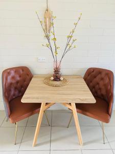 dwa krzesła i drewniany stół z wazonem w obiekcie Pelican Sands Scamander w mieście Scamander