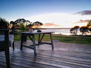 a table on a deck with a view of the water at Pelican Sands Scamander in Scamander