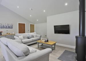 a living room with two couches and a flat screen tv at Bluebell Cottage in Beccles