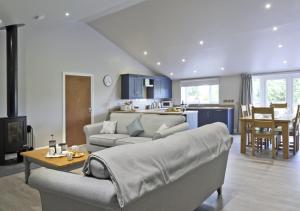 uma sala de estar com um sofá, uma mesa e uma cozinha em Bluebell Cottage em Beccles