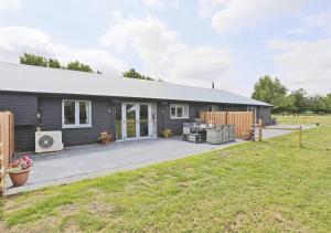 a gray house with a patio and a yard at Bluebell Cottage in Beccles