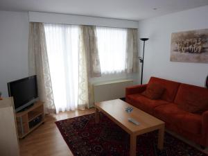 a living room with a red couch and a coffee table at Apartment Casa Lisabetha by Interhome in Engelberg