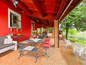 een patio met een rode muur en tafels en stoelen bij Holiday Home La Letizia by Interhome in Collemancio