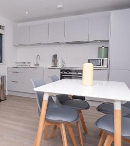 a white kitchen with a white table and chairs at 8 Middlecombe - Luxury Apartment at Byron Woolacombe, only 4 minute walk to Woolacombe Beach! in Woolacombe