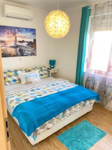 sypialnia z łóżkiem z niebieską pościelą i żyrandolem w obiekcie Apartments Suzy Zadar w mieście Zadar