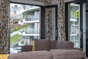 a couch sitting in front of a large glass window at 8 Middlecombe - Luxury Apartment at Byron Woolacombe, only 4 minute walk to Woolacombe Beach! in Woolacombe