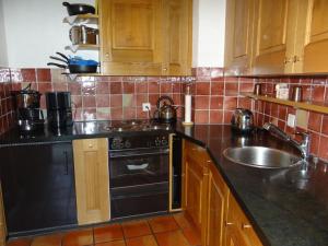 a kitchen with a black stove and a sink at Apartment Am Dürrbach 5-517 by Interhome in Engelberg