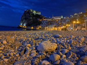 a rocky beach at night with buildings and lights at IL Ritratto casa vacanza in Scilla