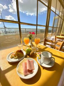 a table with two plates of breakfast food and orange juice at Hotel Atlántico Suites in Mar del Plata