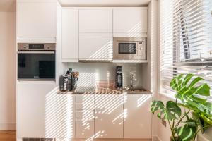 cocina con armarios blancos y microondas en Modern Double Room - Haywards Heath en Haywards Heath