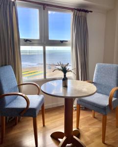 a table and chairs in a room with a view of the beach at Hotel Atlántico Suites in Mar del Plata