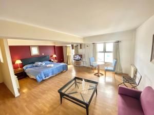 Hotel Atlántico Suites في مار ديل بلاتا: غرفة نوم مع سرير وغرفة معيشة