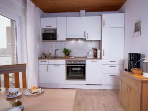 eine Küche mit weißen Schränken und einem Tisch in der Unterkunft Apartment Lachmöwe by Interhome in Norddeich