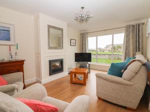 a living room with two chairs and a fireplace at 20 Lighthouse Village in Fenit