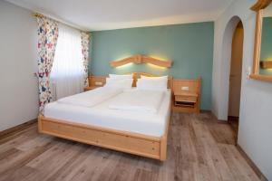 um quarto com uma cama grande e lençóis brancos em Landgasthof Hanselewirt em Schwangau
