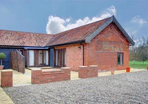 a red brick house with a red roof at Buttercup Lodge in Darsham