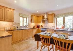 a kitchen with wooden cabinets and a table with chairs at Buttercup Lodge in Darsham