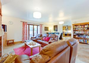 a living room with a leather couch and a table at Buttercup Lodge in Darsham