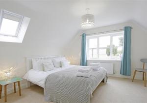 a white bedroom with a bed with towels on it at Camomile Cottage in Friston