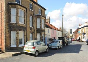 two cars parked on a street next to a building at Caithness House in Southwold