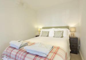 a bedroom with a white bed with towels on it at Caithness House in Southwold