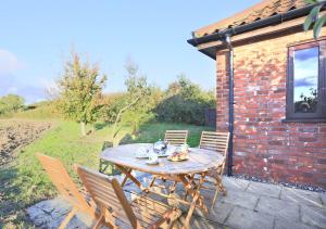 a wooden table and chairs in front of a brick building at Canola Lodge in Darsham