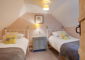 a bedroom with two beds and a lamp on a table at Church Cottage in Wangford