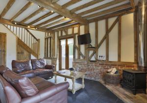 uma sala de estar com sofás de couro e uma televisão em Christmas Cottage Sternfield em Friston