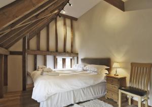 a bedroom with a large white bed and a chair at Christmas Cottage Sternfield in Friston