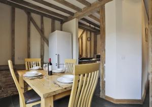 a wooden table with chairs and a white refrigerator at Christmas Cottage Sternfield in Friston