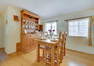 a dining room with a wooden table and chairs at Clematis Cottage in Lavenham