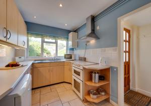 a kitchen with blue walls and wooden cabinets at Clematis Cottage in Lavenham