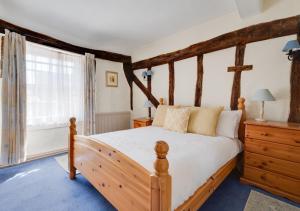 a bedroom with a wooden bed and a window at Clematis Cottage in Lavenham