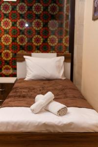 a bed with two rolled towels on it at Qala Hostel Ganja in Ganja +29 photos