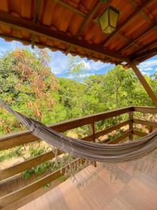 a hammock on a deck with a fence at Topo do Cipó Ecopousada Vegana in Serra do Cipo